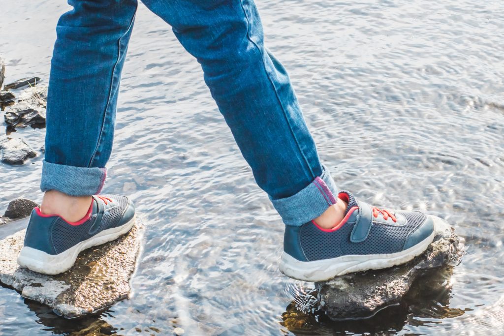 Person Walking On Stones In River