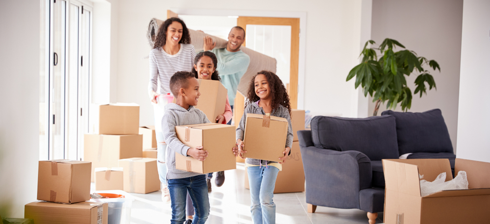 Smiling Family Carrying Boxes Into New Home On Moving Day ©Monkey Business Images