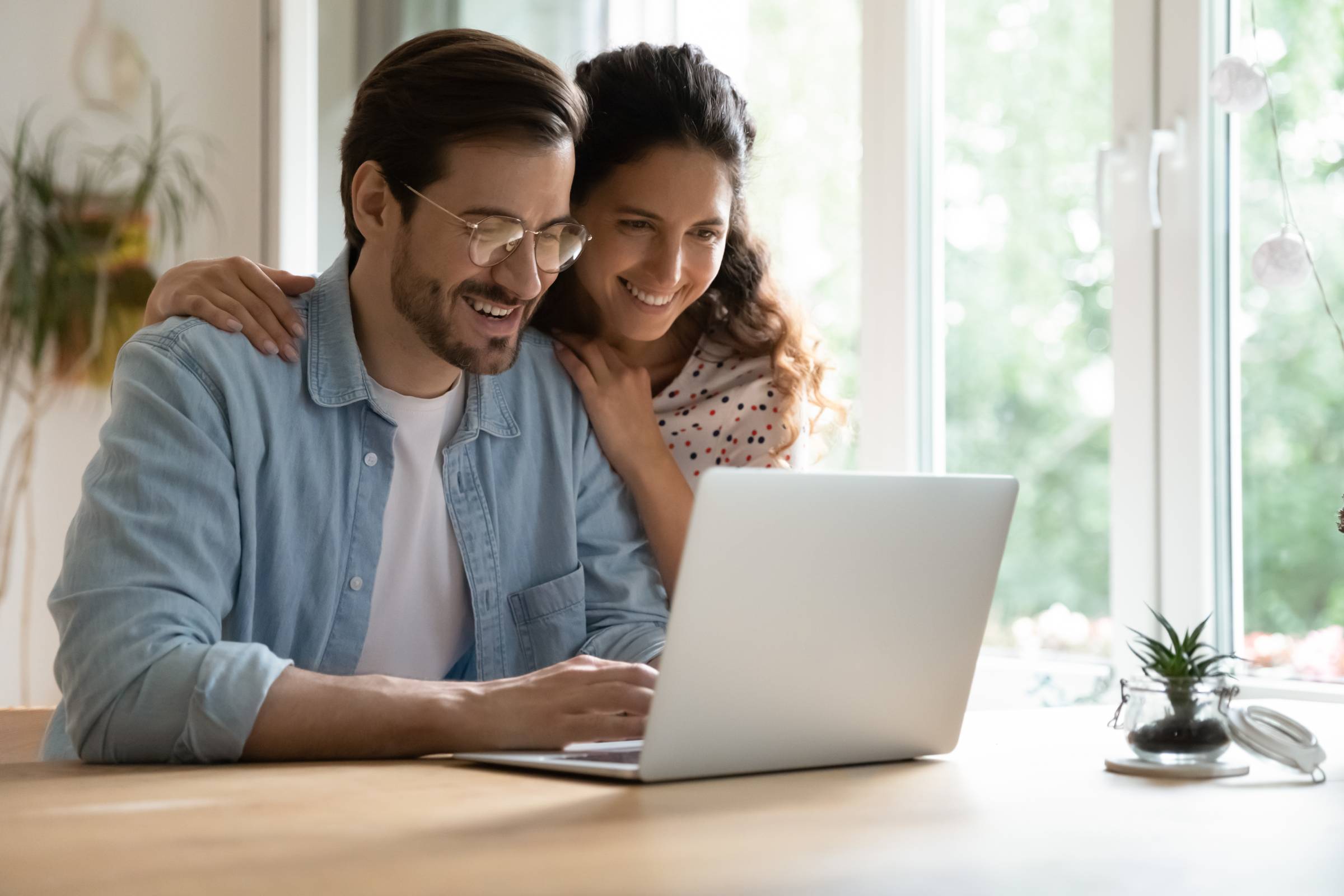 a young couple smiling at their laptop