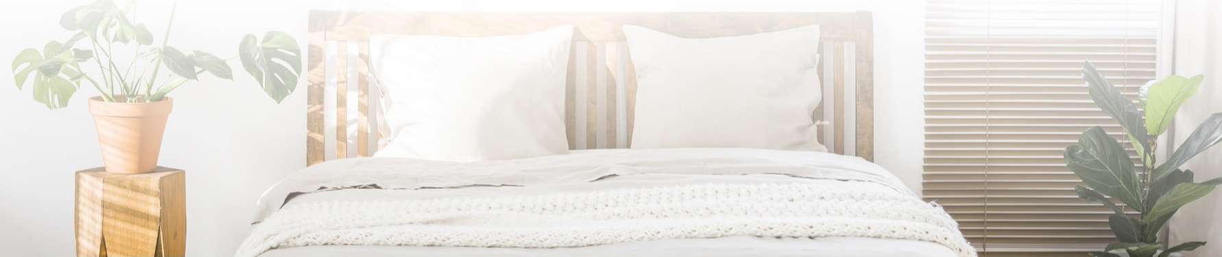 Bedroom decorated in muted tones with plants on either side of the bed
