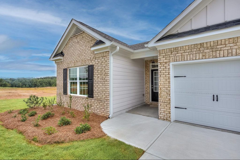 Exterior of a new Peachtree Building Group home in Macon, GA, with a landscaped yard and blue sky