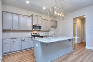 Modern kitchen with island in a new construction home featuring the Woodbury floor plan