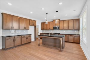 Modern open-concept kitchen with large island and wood cabinetry in a Villa Rica new home

