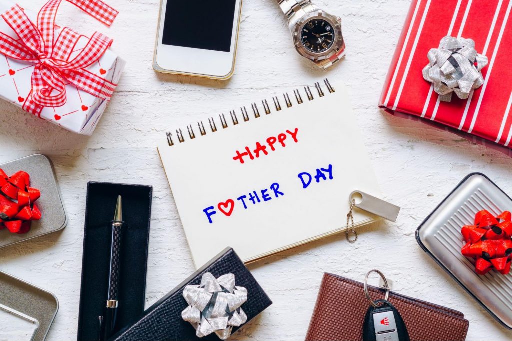 Happy Father’s Day card surrounded by gift boxes, a watch, and car keys on a white background.
©ezphoto