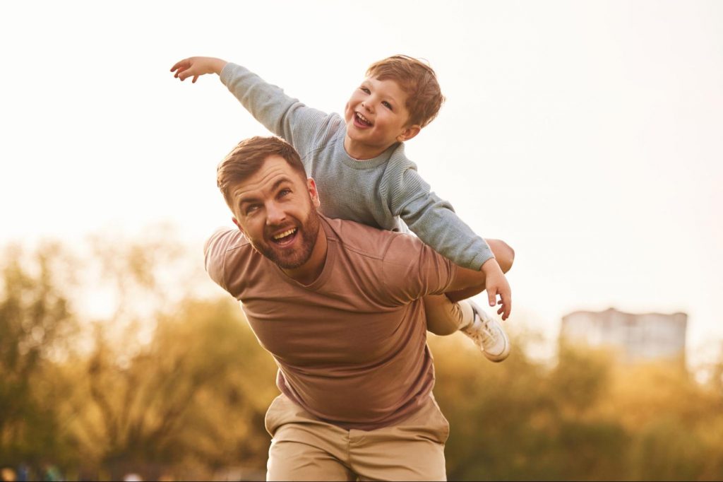 Father giving his young son a piggyback ride in a sunny park.
©Standret