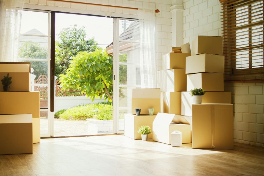 Stacks of cardboard moving boxes next to a glass sliding patio door
©chalermphon_tiam