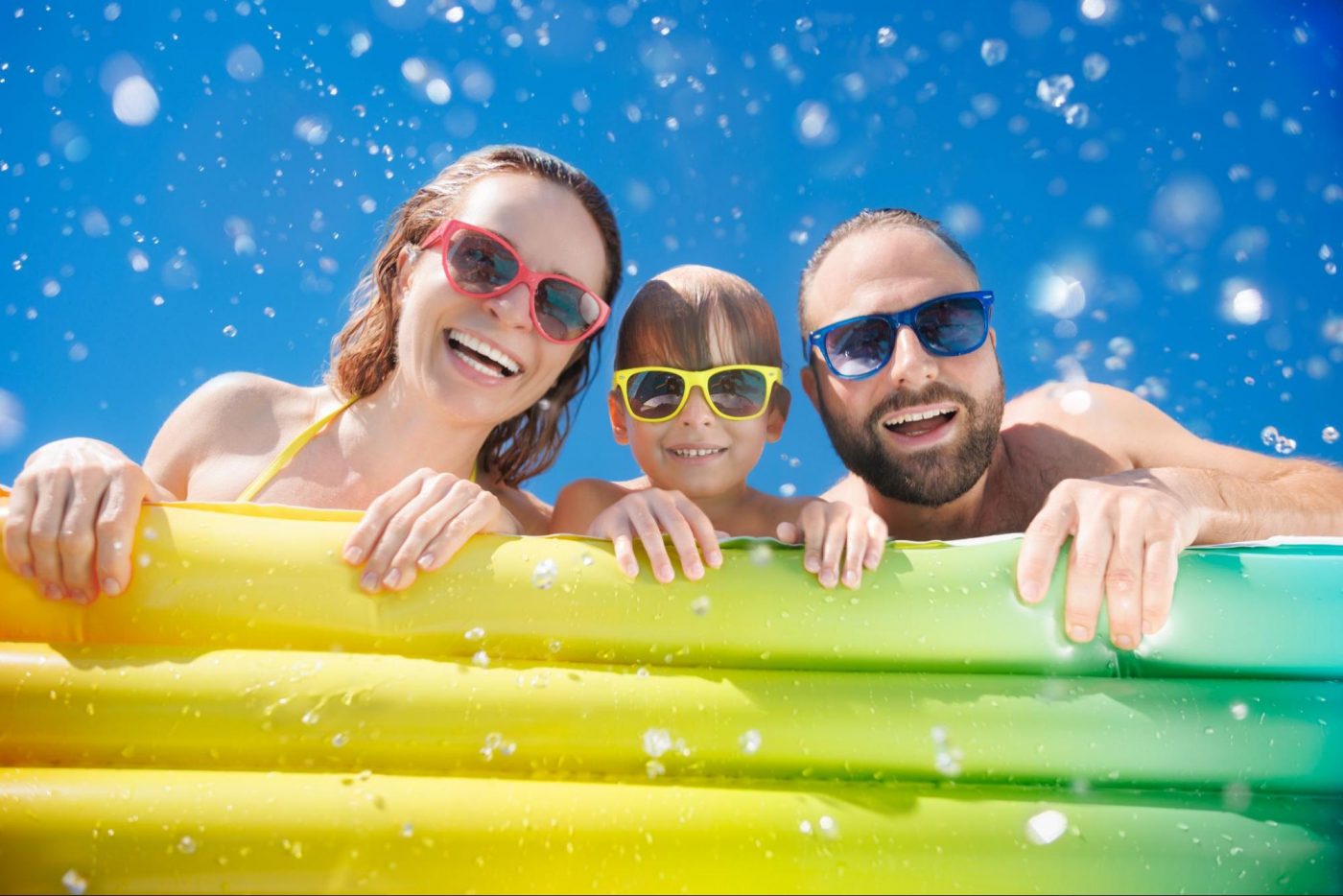Family smiling and splashing in a swimming pool on a hot summer day at Chimney Oaks. ©Sunny studio